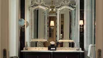 A luxurious bathroom with a large mirror, a chandelier, and a bathtub.