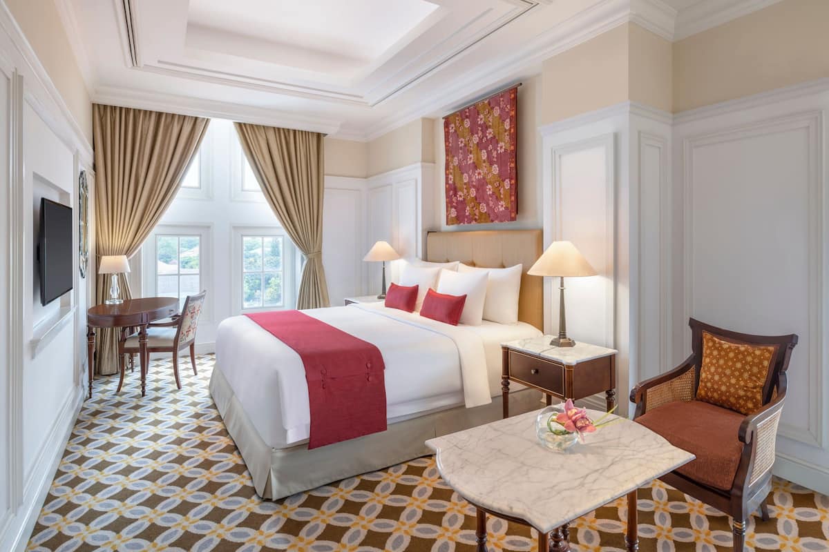 A hotel room with a large bed, two bedside tables, a desk, and a chair.