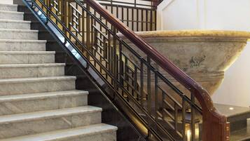 A marble staircase with a wooden handrail and black metal balusters.