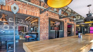 A spacious bar area with a long wooden counter, brick walls, and exposed ceiling beams. - RAVEL Hotel Cyrano (Waimes)