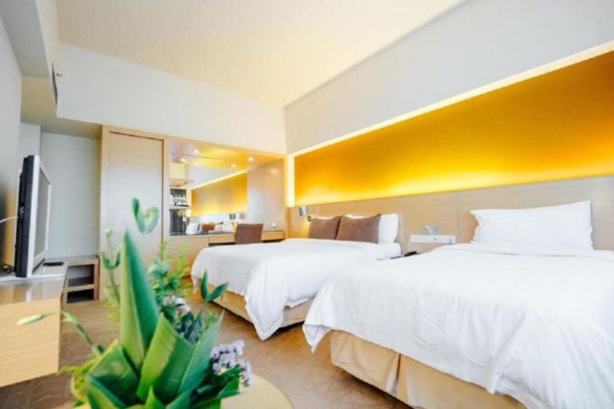 Habitació d'hotel moderna amb dos llits, una televisió i un mirall.