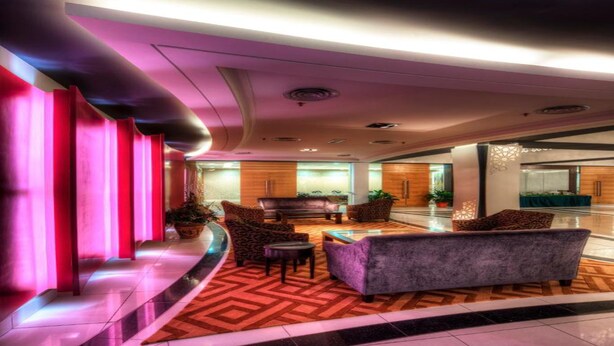 A modern lobby with a curved seating area, a reception desk, and a dining area.