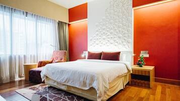 A modern hotel room with a large bed, a decorative wall panel, and a small side table with a plant.