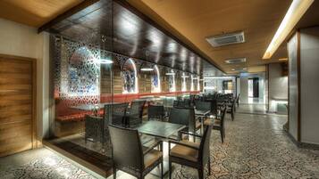 A modern hotel lobby with glass partitions, comfortable seating, and a patterned carpet.