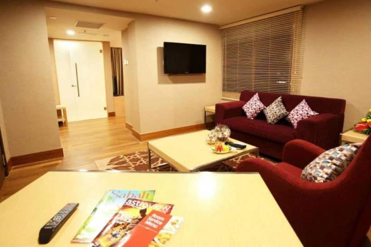 A living room with a red sofa, a coffee table, and a TV on the wall.