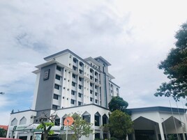 A multi-story hotel with a modern architectural design, featuring a prominent entrance with a signboard.