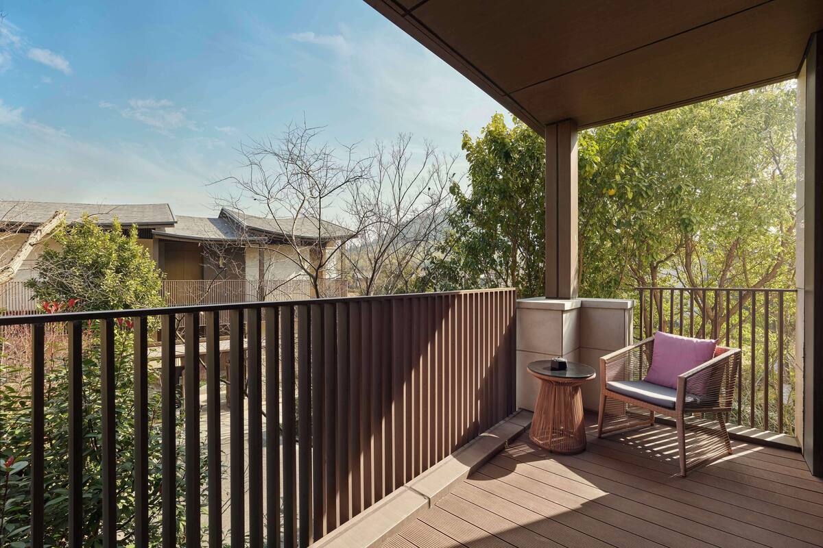 A balcony with a view of neighboring buildings and trees.