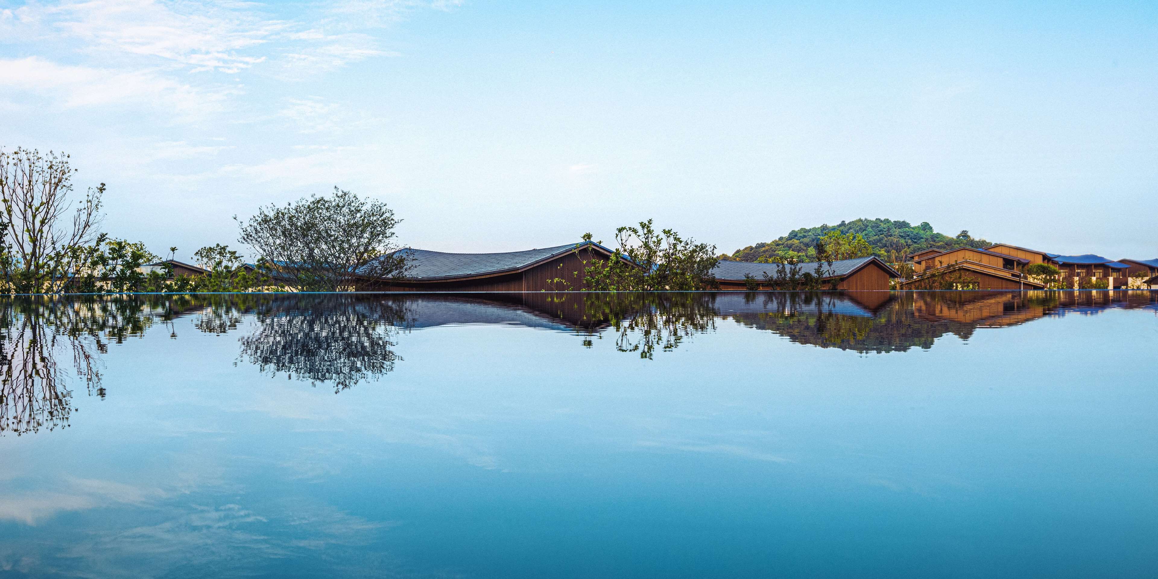 A tranquil lakeside setting with traditional wooden buildings reflecting on the water.