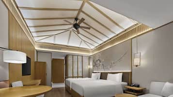 Une chambre d’hôtel moderne équipée d’un grand lit, d’un bureau, d’un canapé et d’un ventilateur de plafond.