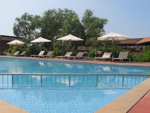A swimming pool with lounge chairs and umbrellas. - The International Centre Goa (Panaji)