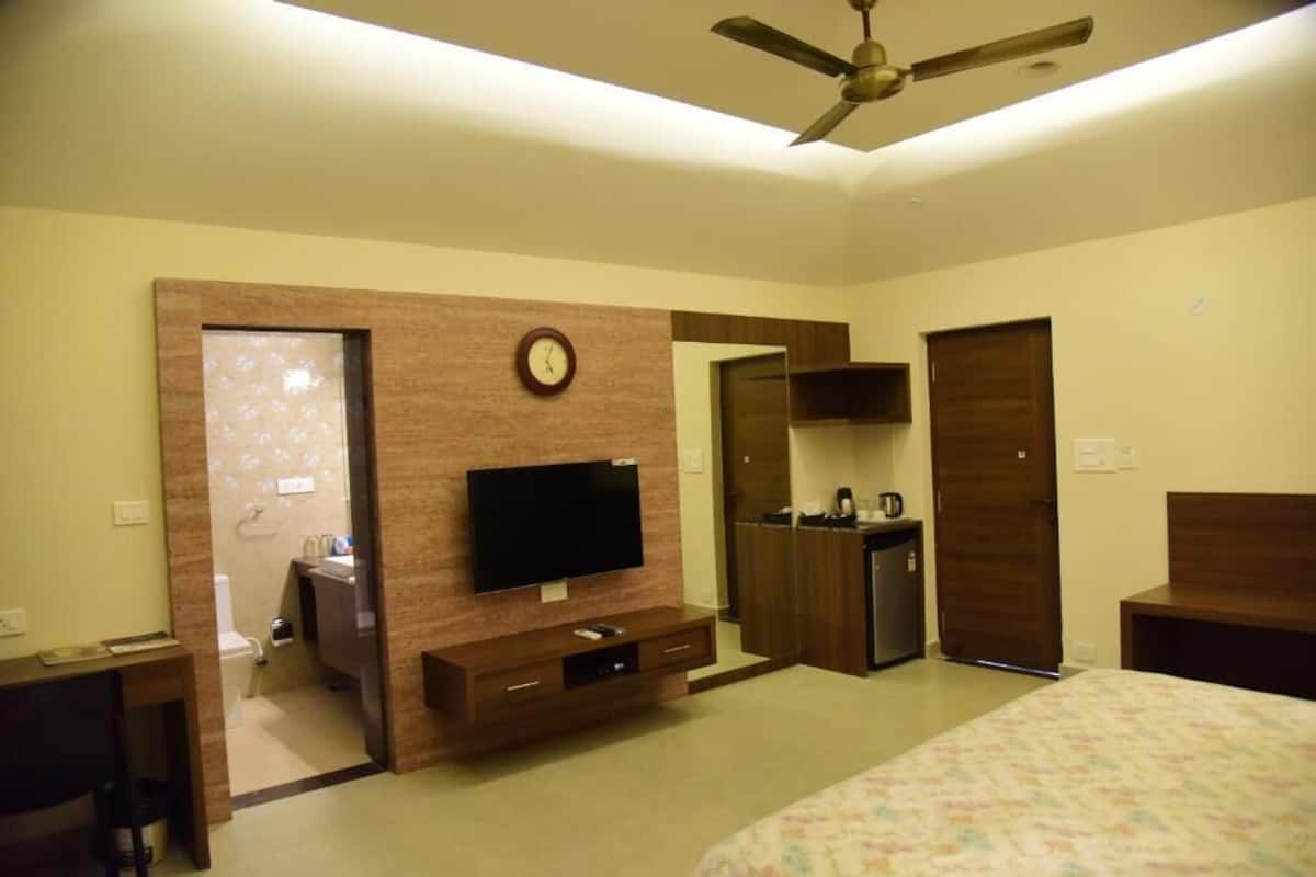 Habitación de hotel con cama, televisor, escritorio, armario y baño.