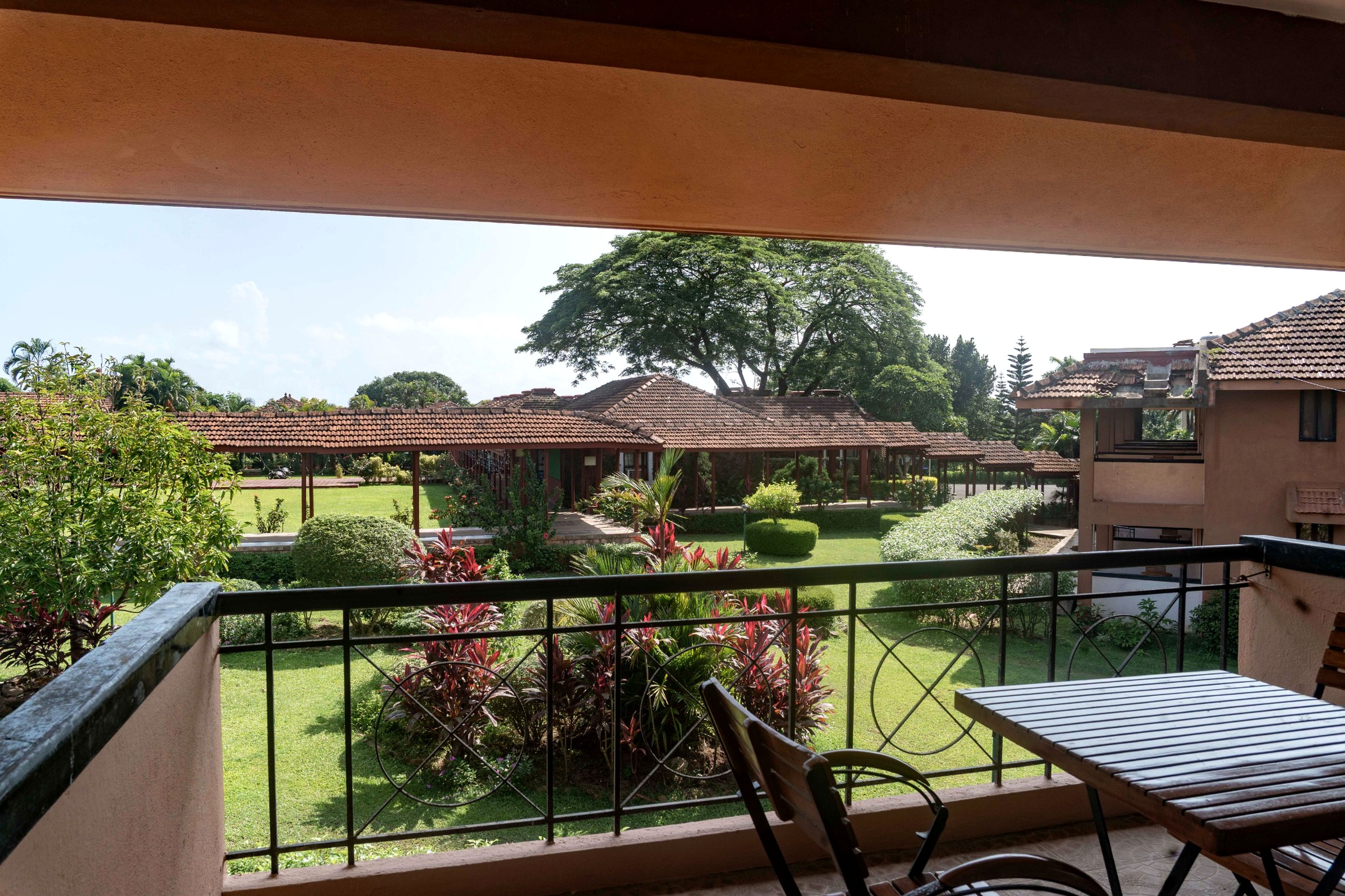 Un balcón con vistas a un patio, una mesa de madera y sillas.