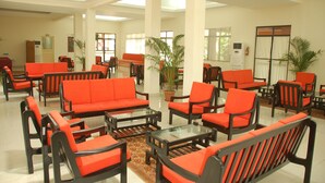 A lobby with orange sofas and chairs, a coffee table, and potted plants. - The International Centre Goa (Panaji)