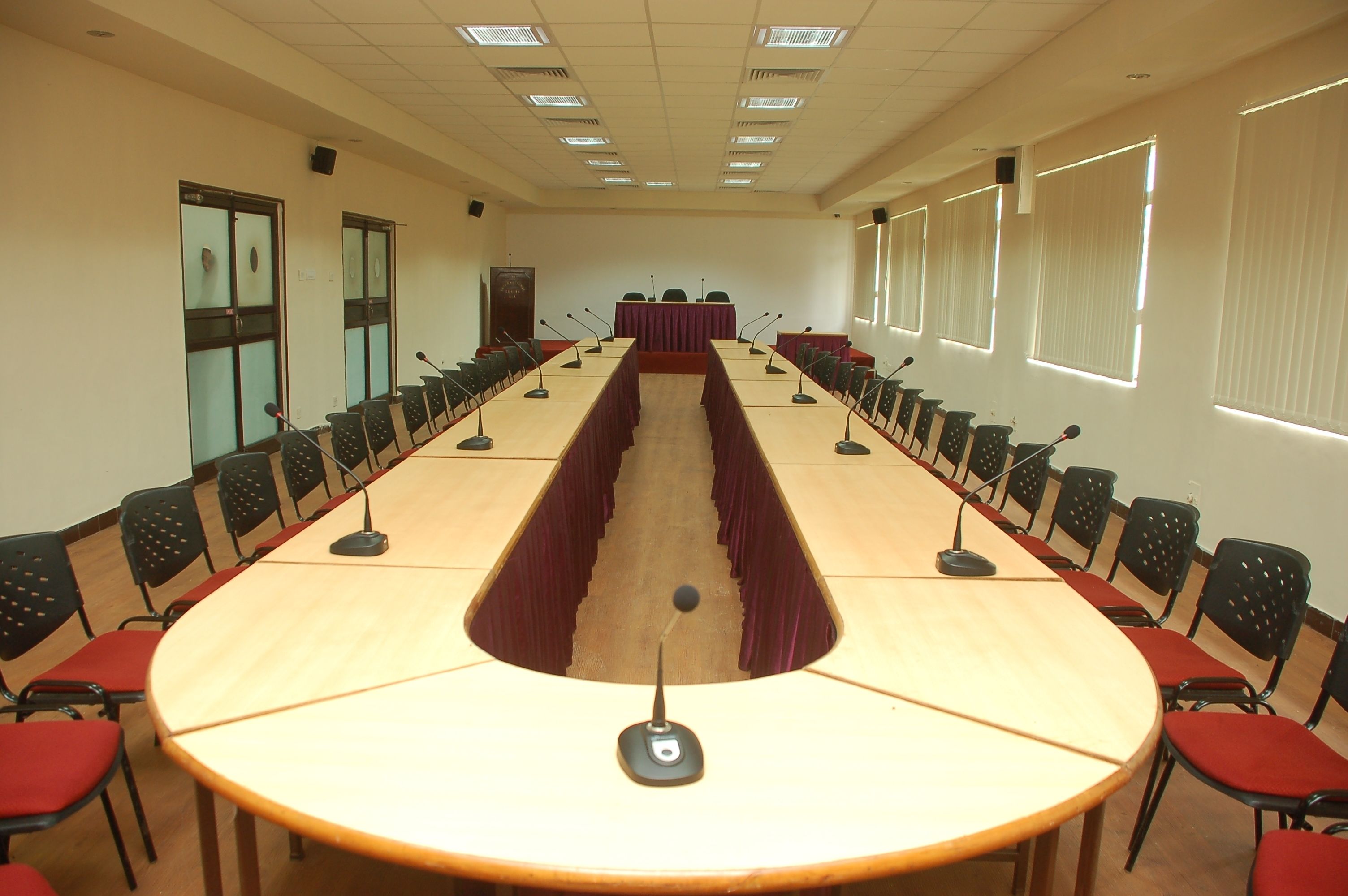 A conference room with a long table, multiple chairs, microphones, and a podium.