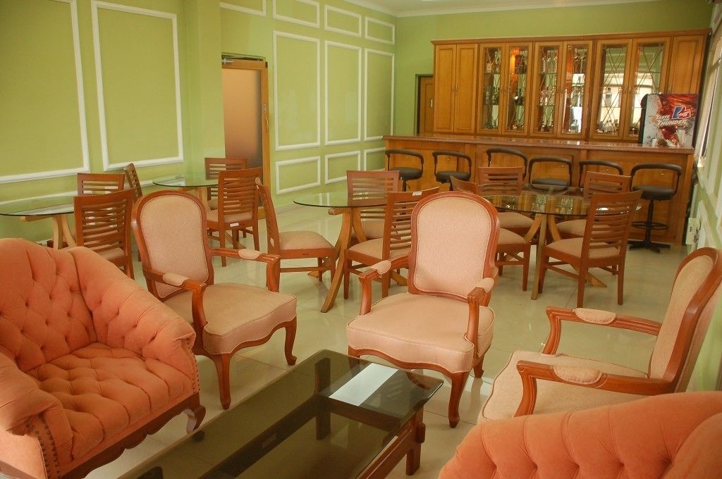 A room with a dining table surrounded by wooden chairs, a sofa, and a cabinet with glass doors.