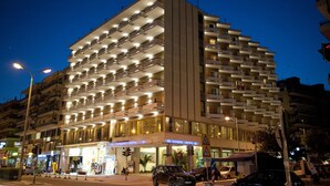 Un hotel de varios pisos con balcones, un restaurante a nivel de calle y una entrada visible.