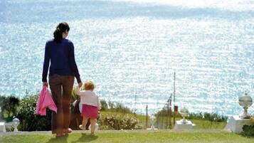 A woman and a child walking on a path with a view of a sparkling body of water.