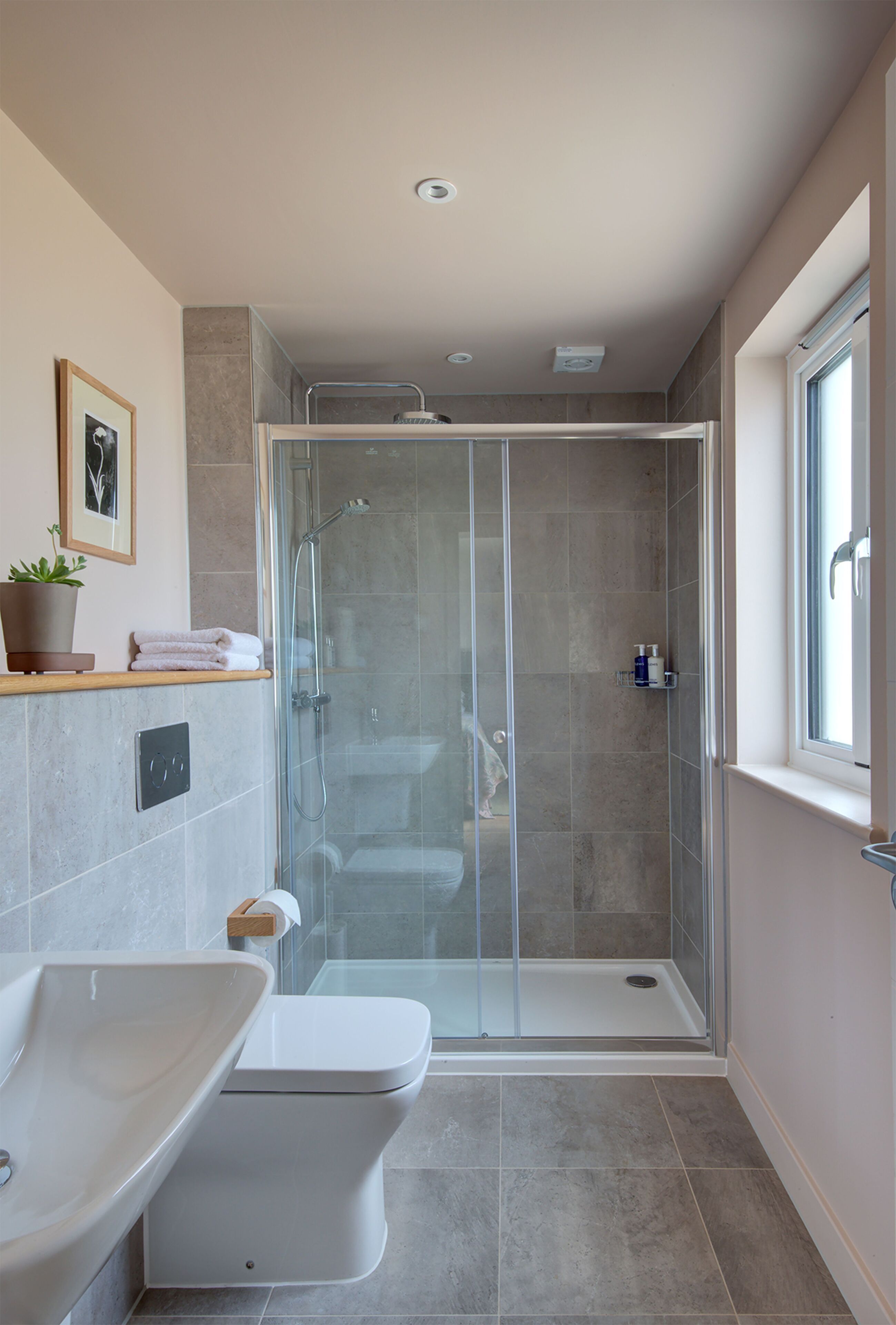 Een moderne badkamer met een douchecabine van glas, een wit toilet en een wastafel.