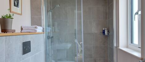 Een moderne badkamer met een douchecabine van glas, een wit toilet en een wastafel.