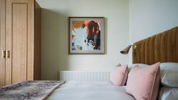 Une chambre à coucher comprenant un lit, un radiateur, une armoire en bois et un tableau abstrait encadré accroché au mur.