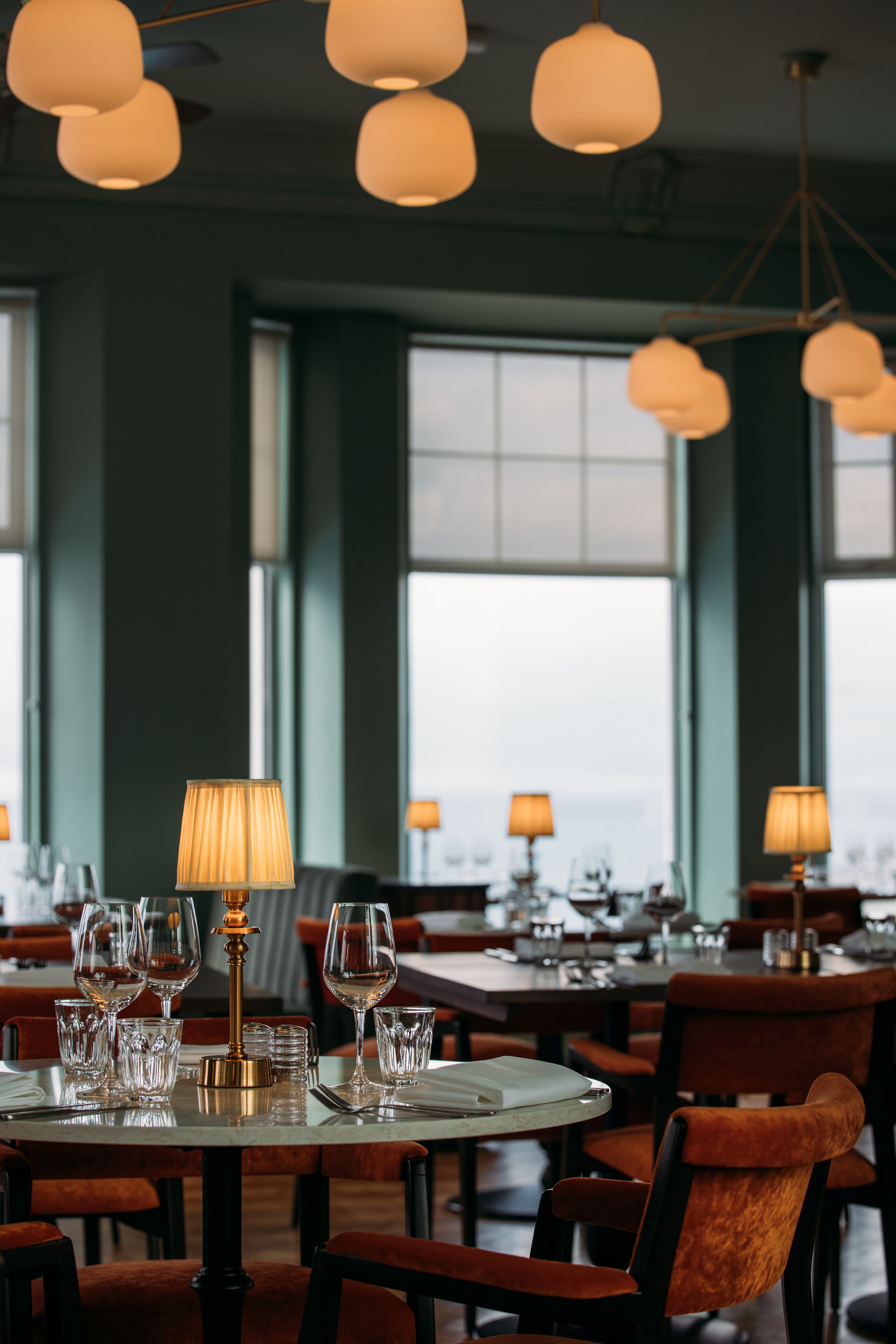 Ein Restaurant mit runden Tischen, Stühlen und hängenden Pendelleuchten.