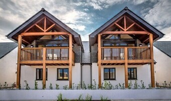 Un edificio simétrico con dos balcones, cada uno con barandilla de madera y un ventanal pequeño.