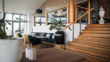 A modern interior with a staircase, wooden flooring, a green sofa, and a large plant.