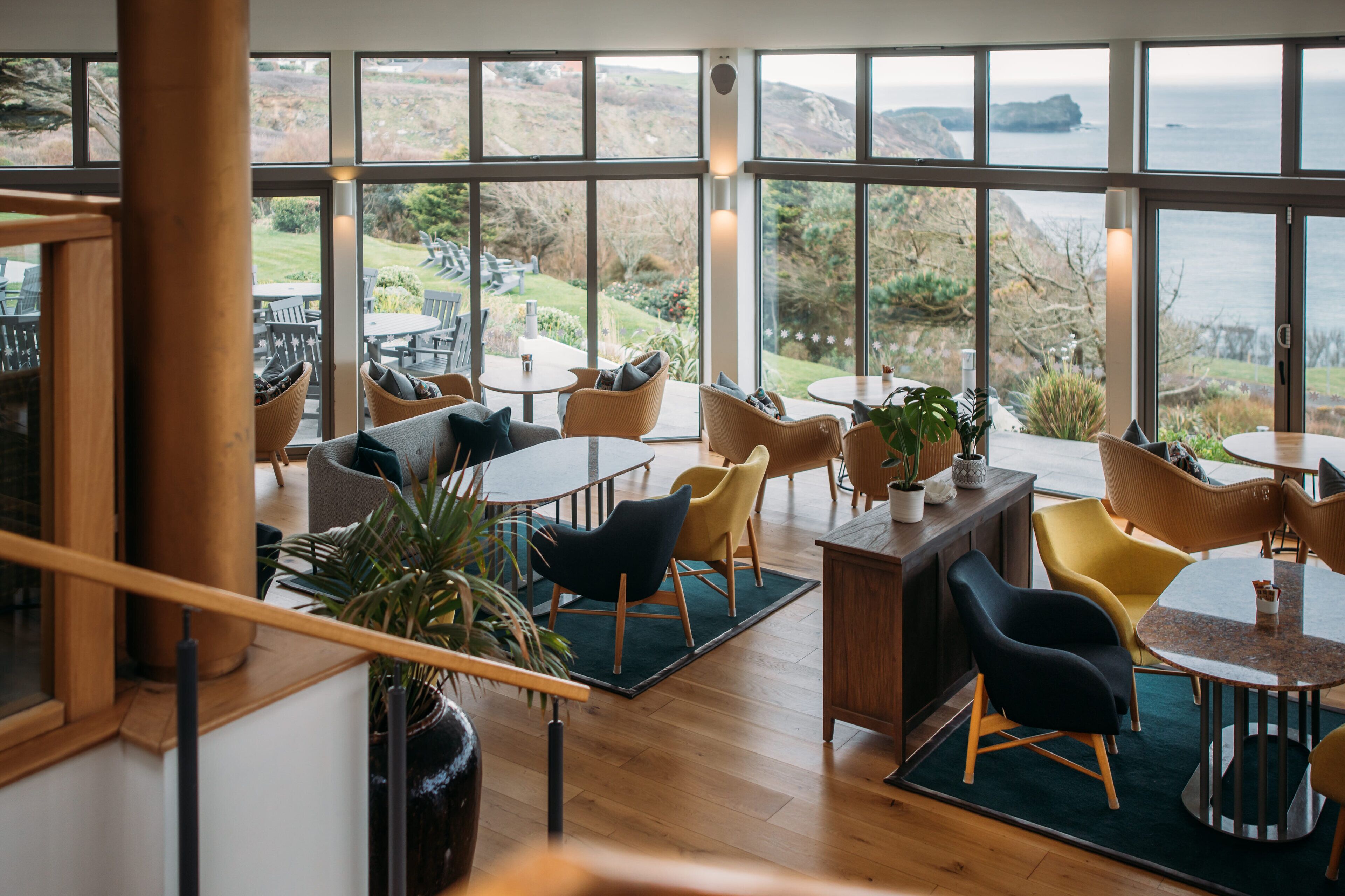 Un comedor espacioso con techos altos y ventanas grandes que ofrecen vistas al mar y a las colinas.