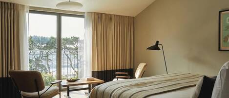 Habitación de hotel con cama, escritorio, silla y vistas al exterior.