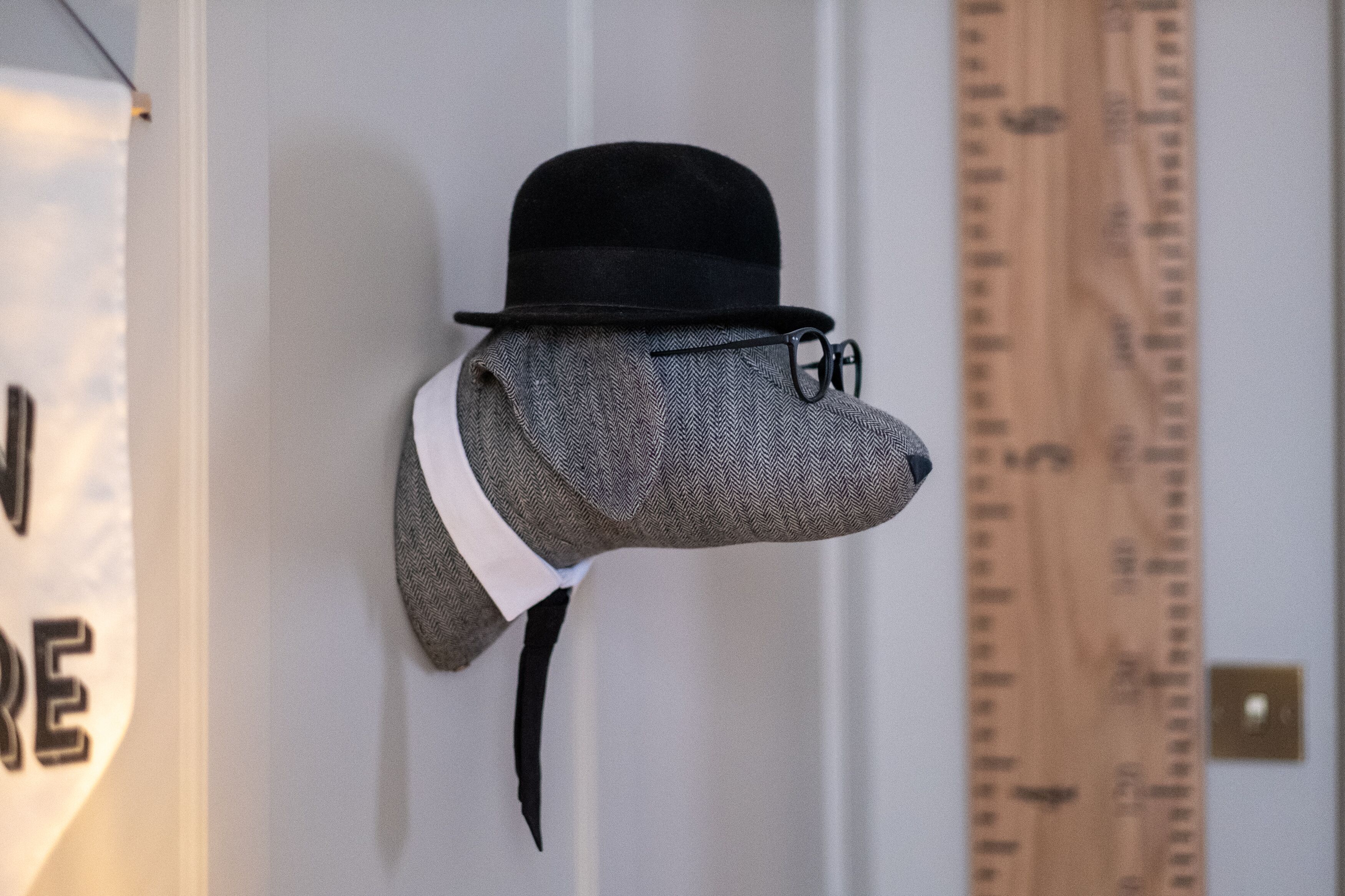 A head-shaped sculpture with a black hat and glasses, mounted on a wall.