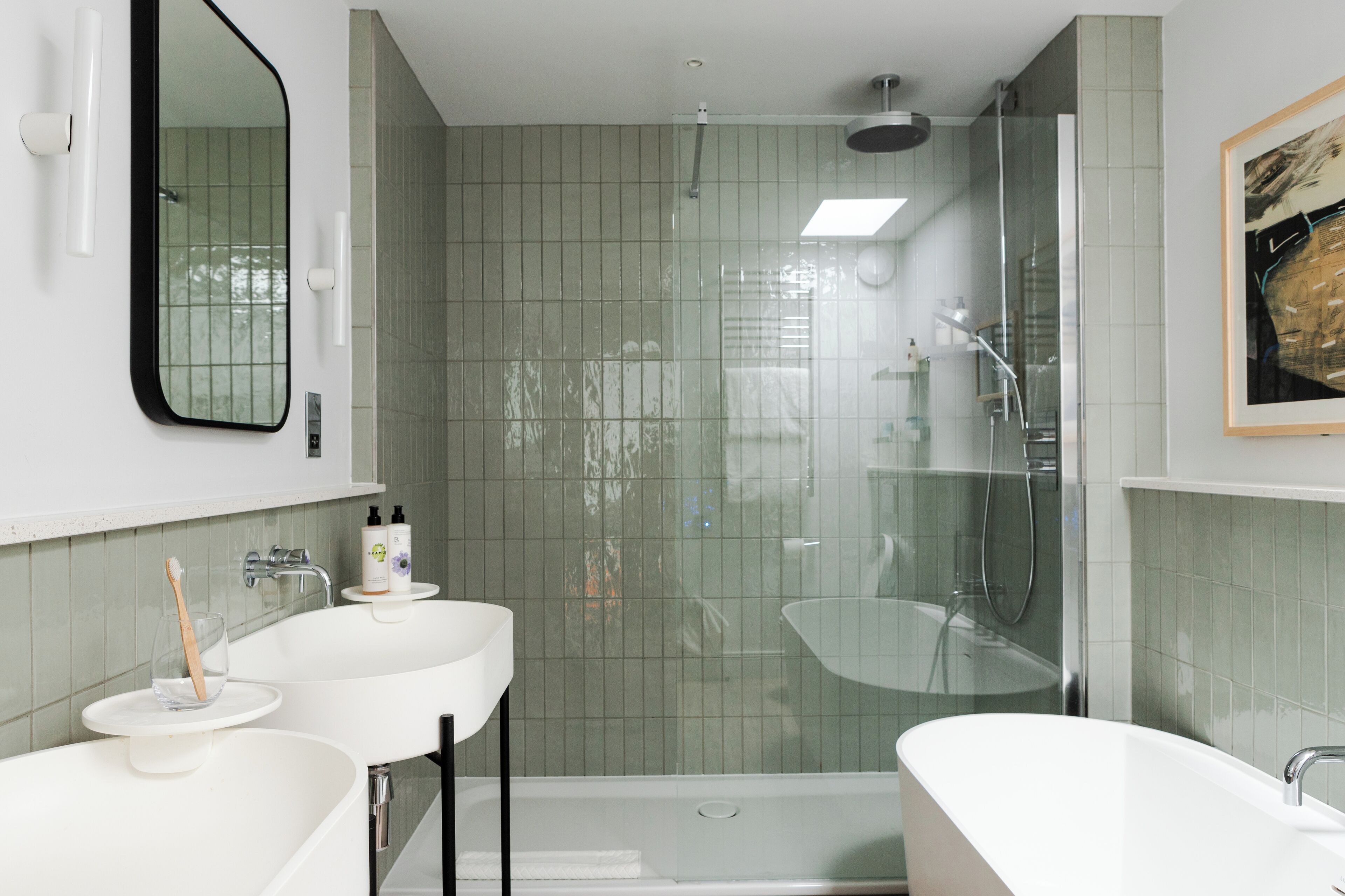 Een moderne badkamer met een grote spiegel, twee wasbakken, een douche en een bad.