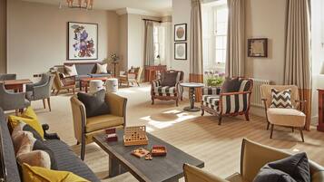 A spacious living room with a sofa set, armchairs, a coffee table, and a fireplace.