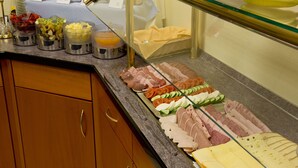 Un bufé con diversas carnes, quesos y frutas.