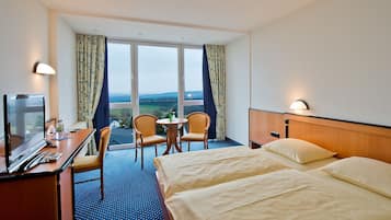 Et hotelværelse med seng, skrivebord, stol, fjernsyn og udsigt til landskabet.