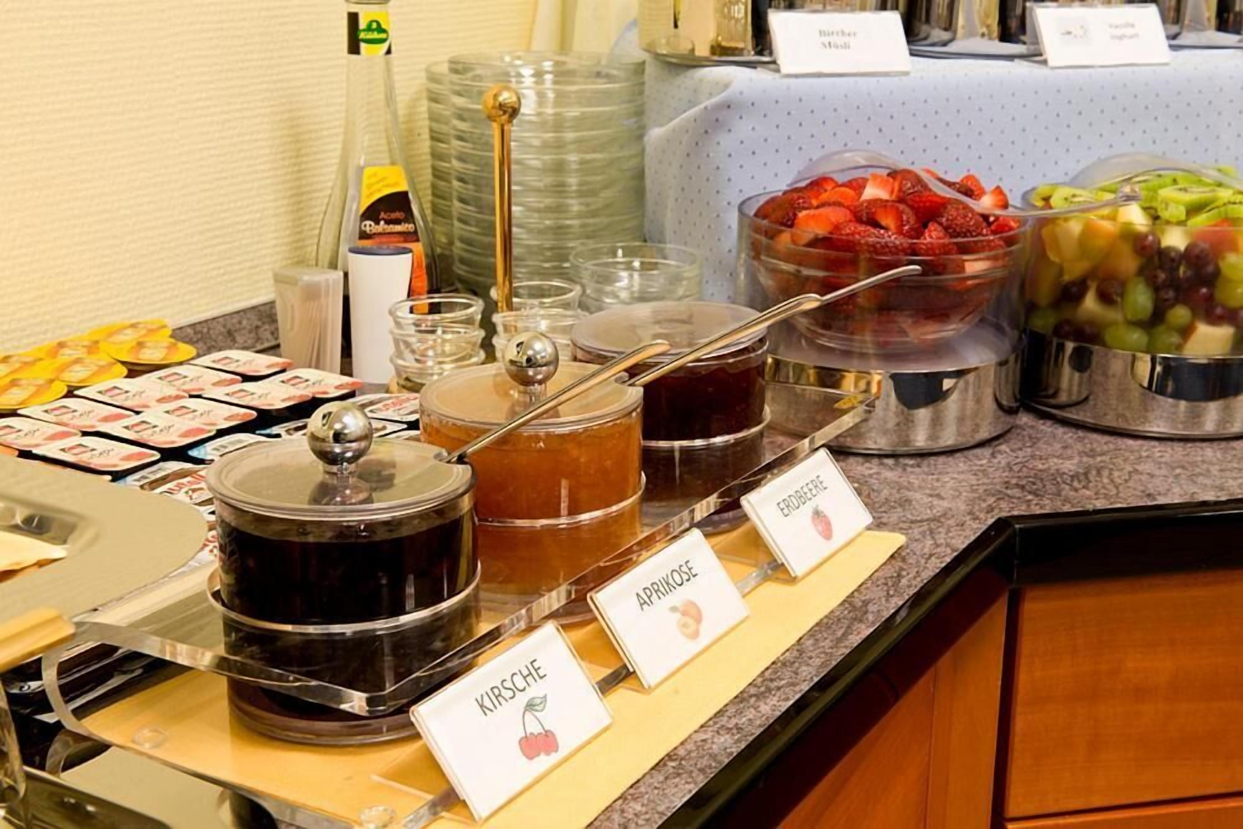En buffet med mærkede beholdere med abrikosmarmelade, kirsebærmarmelade og hindbærmarmelade.