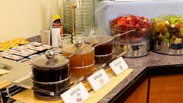 En buffet med mærkede beholdere med abrikosmarmelade, kirsebærmarmelade og hindbærmarmelade.