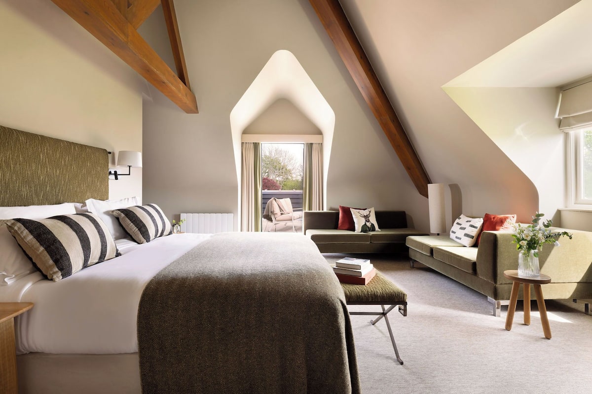 A modern bedroom with a large bed, a sofa, and a small table.