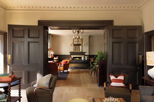 A spacious living room with a fireplace, comfortable seating, and a chessboard.