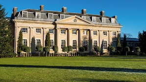 Un grand bâtiment imposant, doté d’une façade symétrique, de nombreuses fenêtres et d’une pelouse bien entretenue à l’avant.