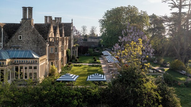 A historic building with a courtyard, outdoor seating, and a garden.