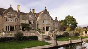 A large, historic stone building with multiple windows and a central staircase leading to a balcony.