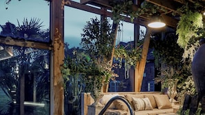 Un espace intérieur chaleureux avec un plafond en bois, un jacuzzi et un canapé agrémenté de coussins.