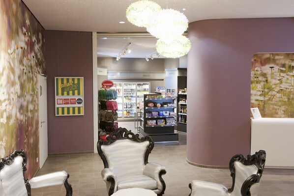 A lobby with a reception desk, a floral mural, and a seating area with ornate chairs. - aja Bad Saarow (Bad Saarow)