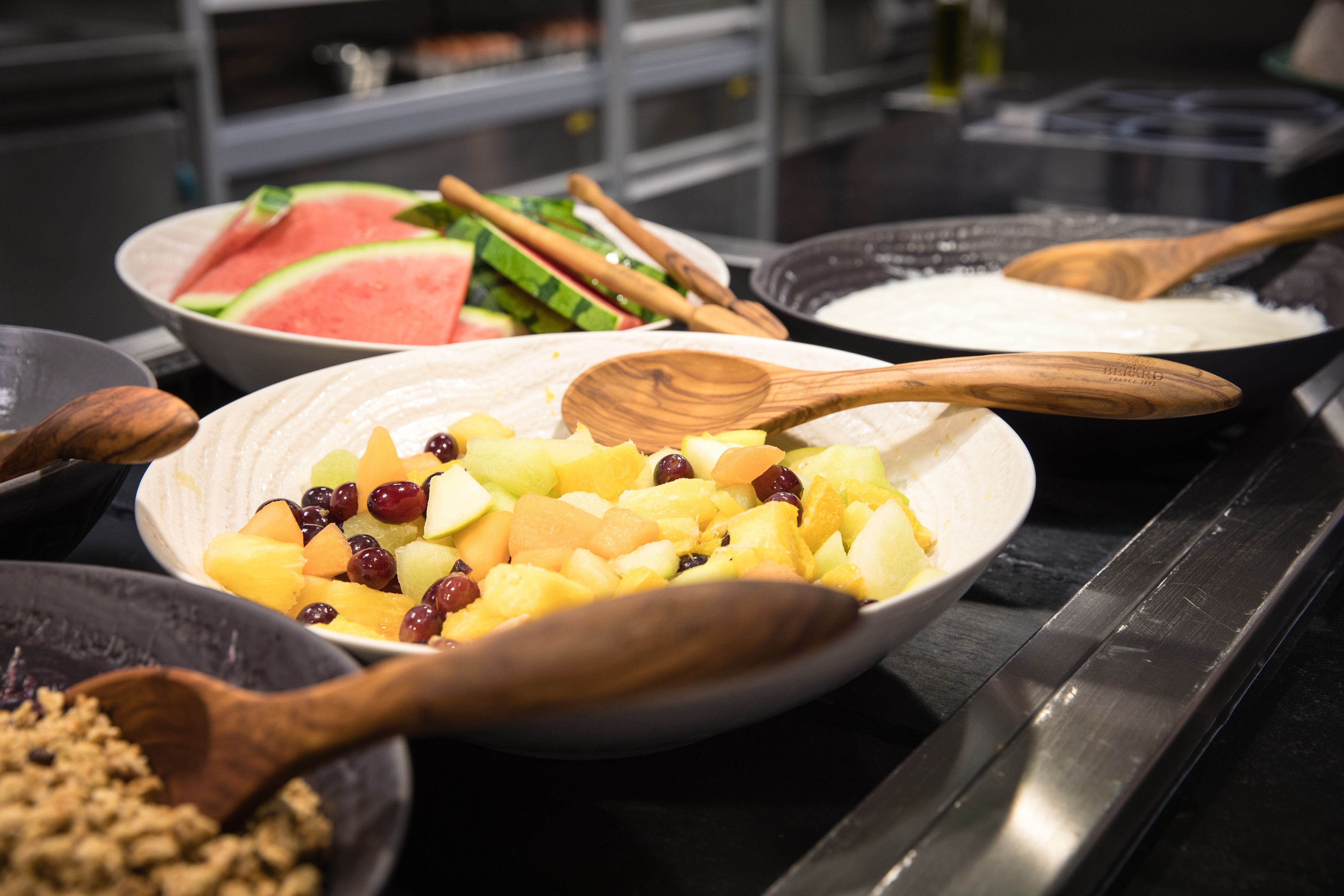 A buffet with various dishes including fruit, vegetables, and a bowl of rice.
