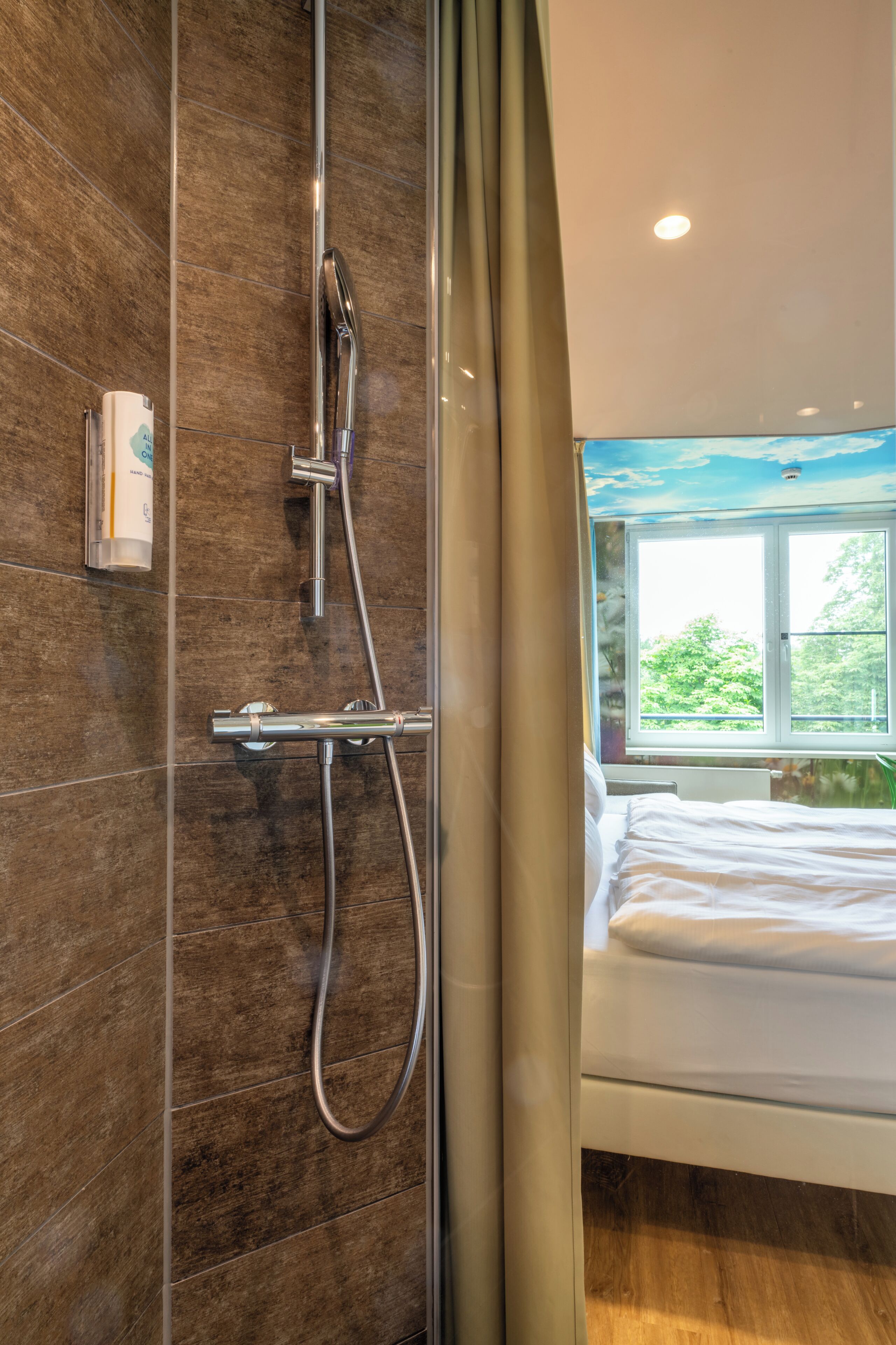 Un baño con ducha, una ventana y una cama.