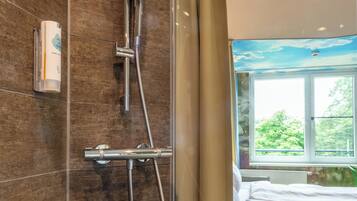 Un baño con ducha, una ventana y una cama.