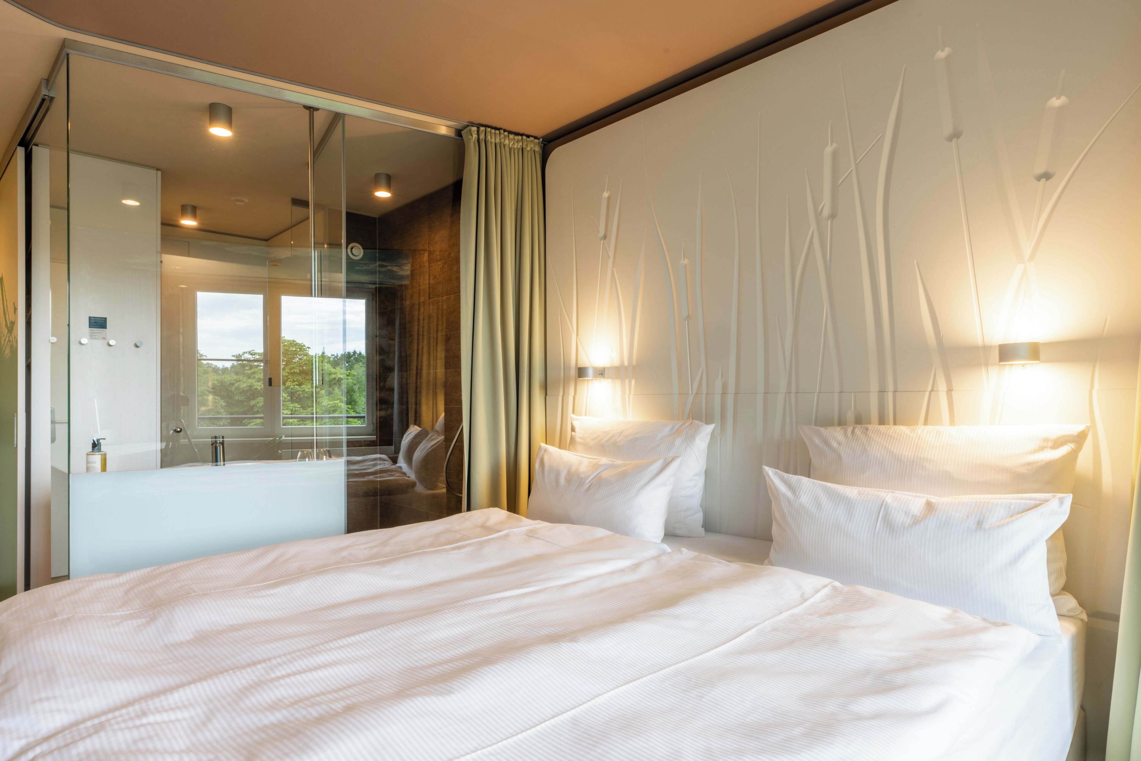Habitación de hotel con una cama grande, un espejo y dos luces fijadas a la pared.