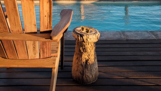 A wooden deck with a pool, a wooden chair, and a tree. - Fish River Lodge (Fish River Canyon)