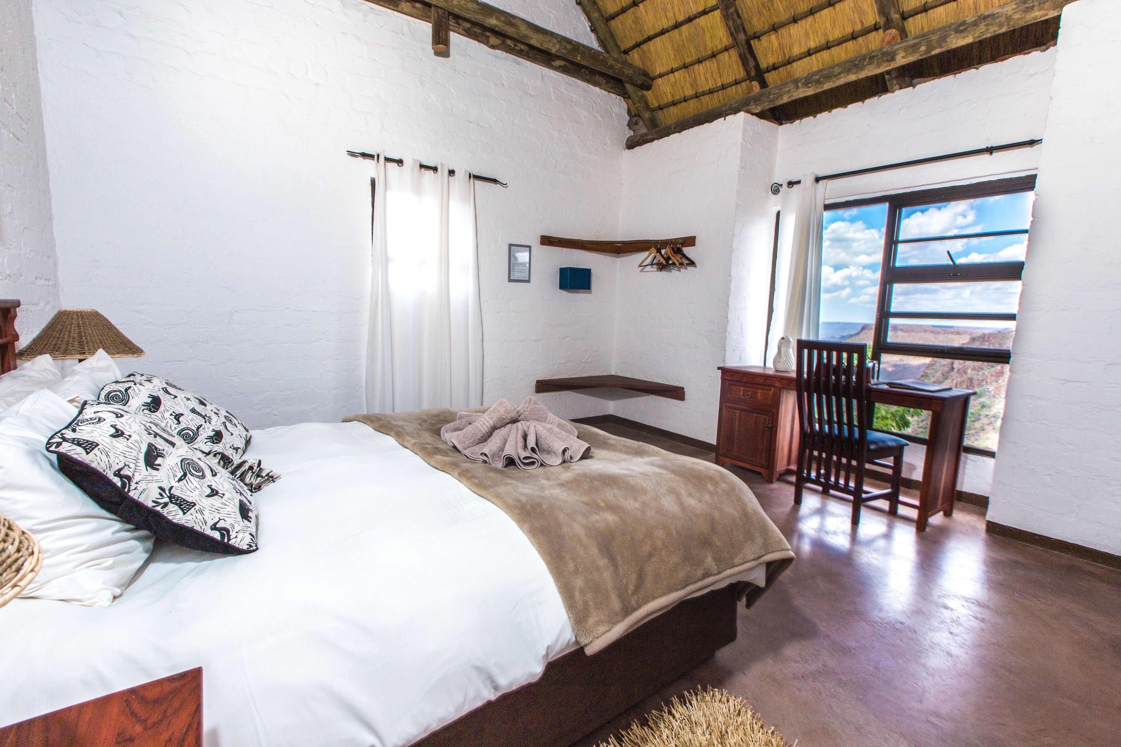 Un dormitorio con una cama, una silla, un escritorio y una ventana con vistas.