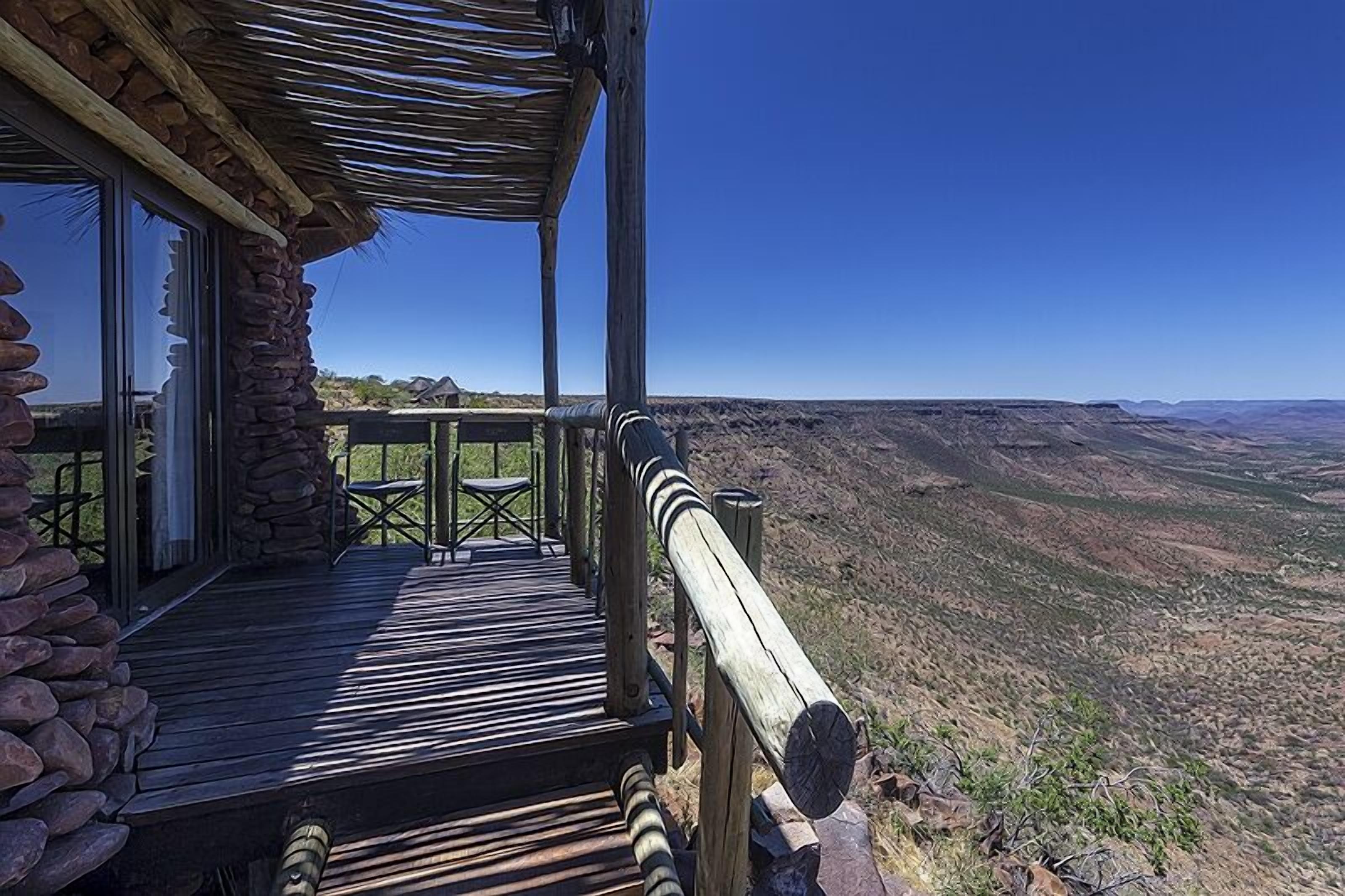 A wooden deck with stone walls, overlooking a vast landscape.